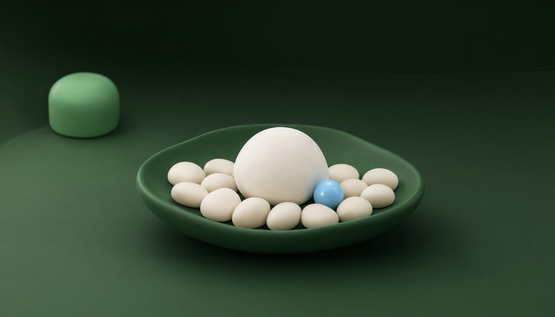 A green bowl filled with small white spheres surrounding one large white sphere and a single blue sphere, with a green rounded object in the background on a green surface