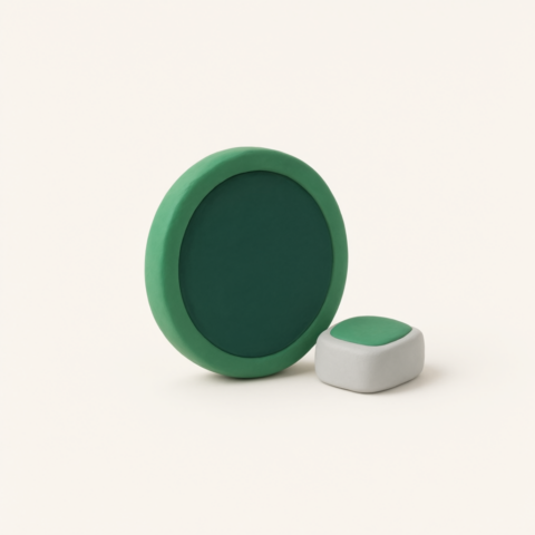 Green clay disc standing on its edge beside a small grey and green block