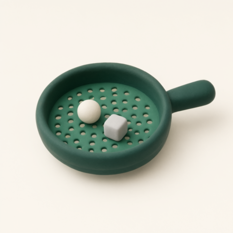 Dark green clay strainer with a perforated base holding a white ball and a small grey cube